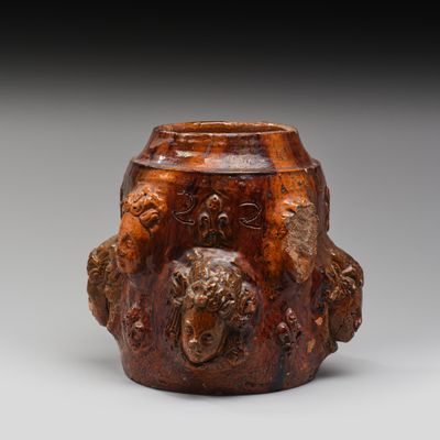 une image représentant un vase marron orné d'une tête de lion