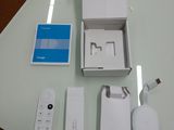 a white box that has a remote, a charger, and other items on a table