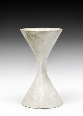 un vase blanc posé sur une table, devant un fond noir