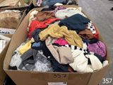 une grande boîte remplie de vêtements posée par terre