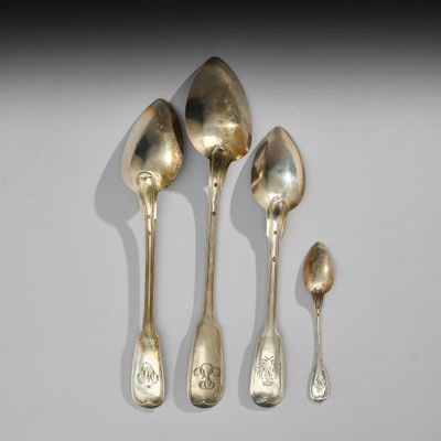 trois cuillères et deux cuillères en argent sur une surface blanche
