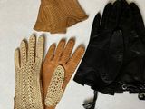 three pairs of leather gloves and a purse on a white surface