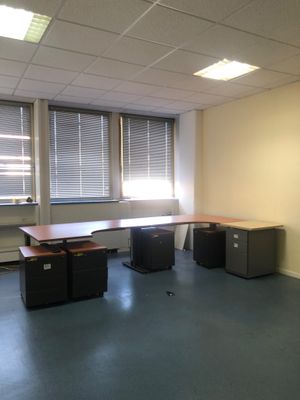 une pièce avec un bureau et deux fenêtres