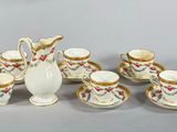 un pichet blanc et six tasses avec leurs soucoupes posés sur une table