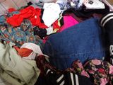 a suitcase full of clothes and clothes sitting on a bed