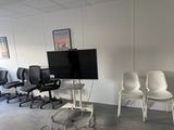 trois chaises dans une pièce où est accrochée une télévision à écran plat au mur