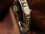 a close up of a gold and silver watch on a brown cloth