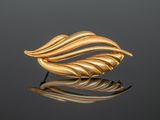 a close up of a gold leaf broochle on a reflective surface