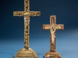 two wooden crosses with beads on them sitting on a blue surface