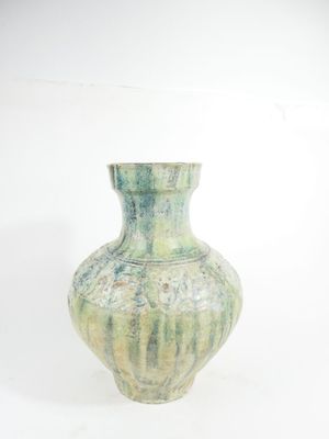 a green vase that is sitting on a white surface