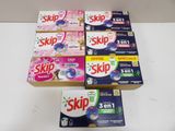 six boîtes de savon « Skip » posées sur une table à côté d'une boîte de dentifrice