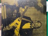 yellow and black photograph of a man with a guitar in a green crate