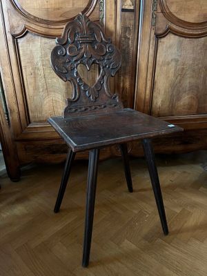 une chaise en bois posée sur un parquet, devant une armoire en bois