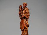 une statue en bois sculpté représentant un homme tenant un enfant dans ses bras