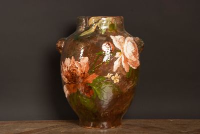 un vase avec des fleurs peintes dessus, posé sur une table