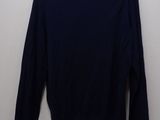 a black sweater on a hanger against a white wall