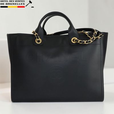un sac fourre-tout en cuir noir avec des chaînes dorées aux anses