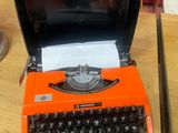 an orange typewriter sitting on a wooden table