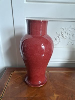 un vase rouge posé sur une table en bois