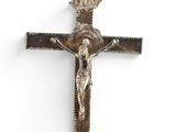 une vieille croix en argent surmontée d'une couronne, sur fond blanc