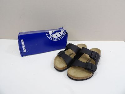 the black sandals are next to a blue box on a white surface