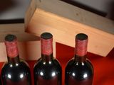 three bottles of red wine sit next to a wooden box