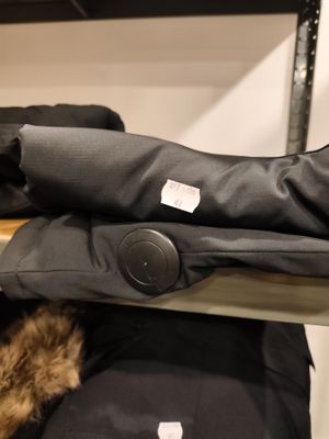 un chat assis dans un sac posé sur une étagère