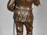 bronze figurine of a man with a sword and a hat