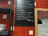 a menu on the wall of a restaurant with red tiles