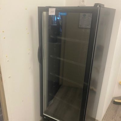 un réfrigérateur à porte vitrée dans un coin de la pièce