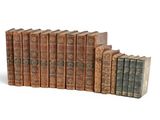 several old books are lined up in a row on a white surface