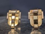 pair of gold toned cufflinks on shiny surface with reflection