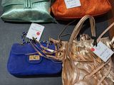 trois sacs à main posés sur une table, avec des étiquettes accrochées dessus