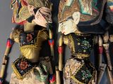 three wooden dolls are sitting on a blue surface, one is wearing a hat and the other is wearing a dress