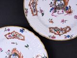 two plates with floral designs on them on a black surface