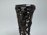 a black vase with carvings on it on a white surface