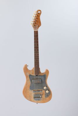an electric guitar hanging from a string on a white wall