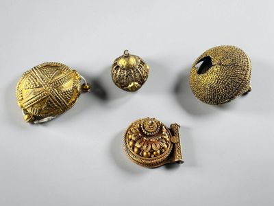 a group of five gold - plated objects including a bell, a ring, and a broochet