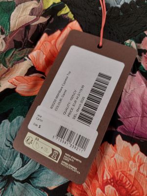 une étiquette sur un tissu à fleurs coloré, accompagnée d'une étiquette de prix
