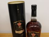 une bouteille de whisky posée à côté d'une boîte noire sur une table en bois