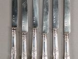 six silverplated knives are lined up next to each other on a table