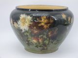 a black vase with yellow and white flowers on it