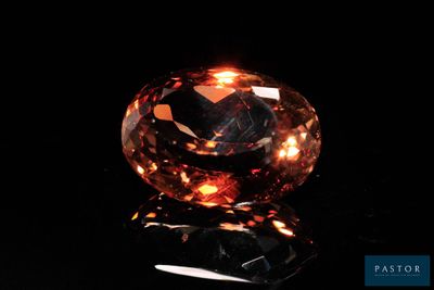 a close up of a fancy orange diamond on a black surface