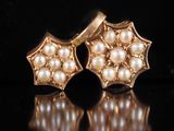 deux paires de boucles d'oreilles en or et perles posées sur un fond noir