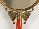 a mirror with a gold frame and a red handle