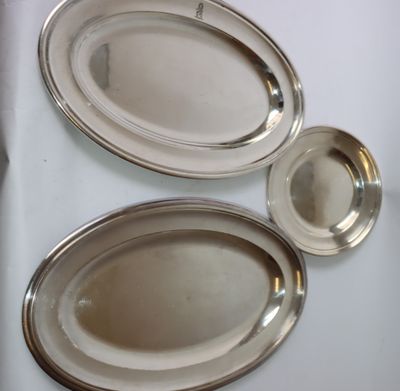 trois plateaux ovales en argent posés sur un plateau de table blanc