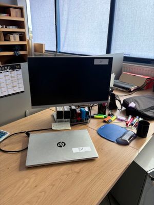 un ordinateur portable posé sur un bureau, devant un écran