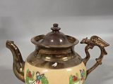 a tea pot with a bird on it sitting on a table