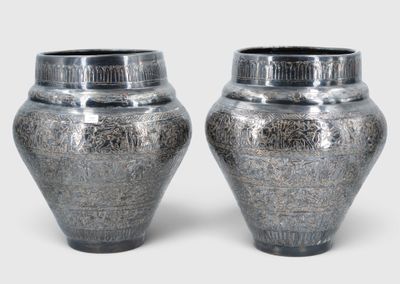 two silver vases sitting next to each other on a white surface