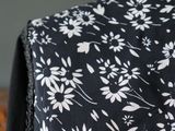 a close up of a black and white dress with white flowers on it